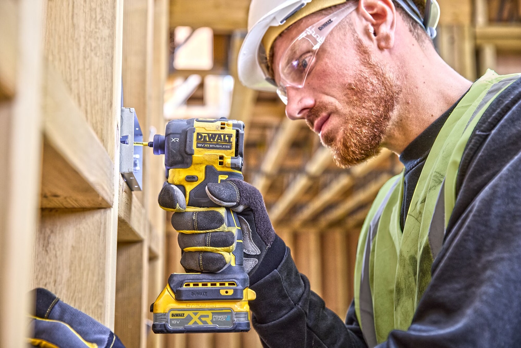 Ouvrier utilisant une visseuse à chocs sans fil DEWALT DCF870NT sur une structure en bois.